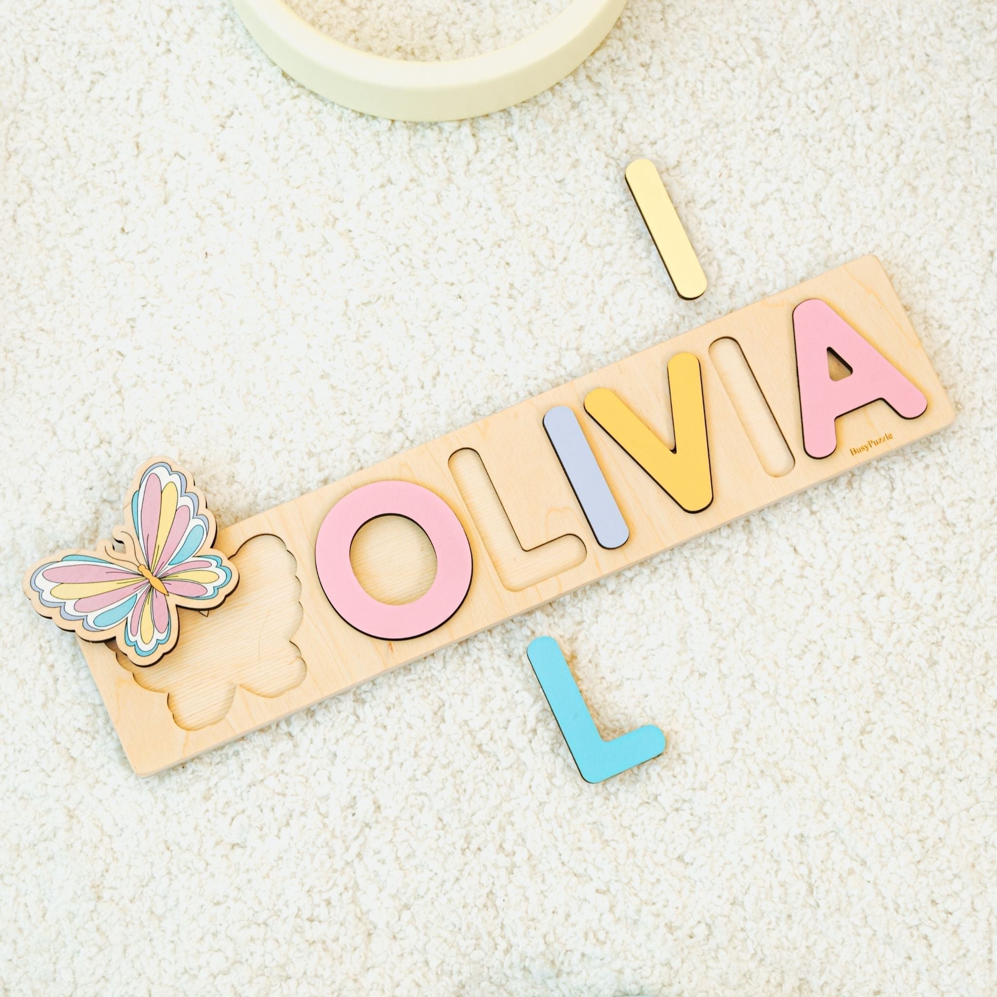 Personalized wooden name puzzle spelling Olivia in pastel colors with butterfly piece, one of the most popular baby names of 2025