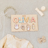 Wooden name puzzle with 'OLIVIA' and decorative charms on a textured surface.
