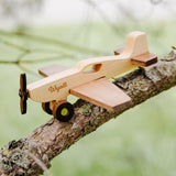 Natural wood airplane toy with engraved name Wyatt on a tree branch outdoors