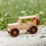 Natural wood off-roader car engraved with the name Lucas on a rock in the grass