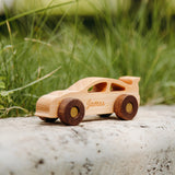 Natural wood car engraved with the name James on a rock outdoors in the grass