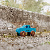Blue personalized wooden pick-up truck on a stone wall outdoors