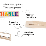 Wooden puzzle with name letters, stand, engraving, and pegs on a white background.