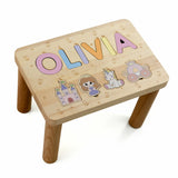 Wooden step stool with colorful letters spelling child`s name and illustrations on a white background