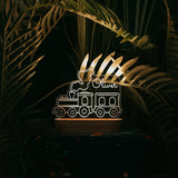 A night light in shape of a train with custom name on a dark background.