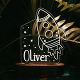 A night light in shape of a rocket with custom name on a dark background.