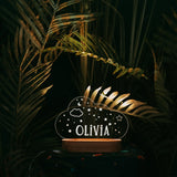 A night light in shape of a cloud with custom name on a dark background.