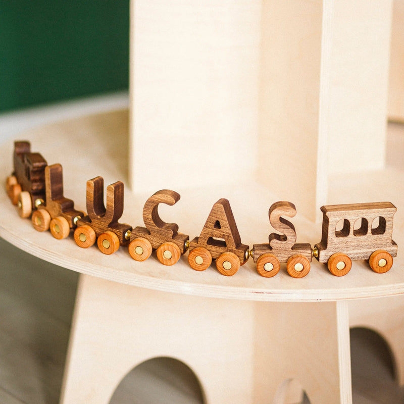 Wooden toy train with letter wagons out on a white surface