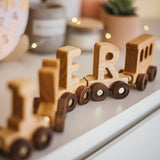 Wooden toy train with letter blocks on a surface