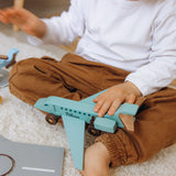 Child playing with a plane toy on a carpeted floor