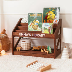 Dark wood personalized Montessori bookshelf with the name Emma's Library, filled with children's picture books in a cozy nursery