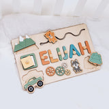 Wooden name board with colorful letters spelling 'ELIJAH' and various shapes on a white background