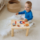 Child playing with a wooden name puzzle stool on a soft surface