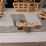Wooden airplane toy with engraved name Oliver next to a toy airport garage set