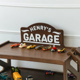 Close-up of a dark wood personalized garage sign reading Henry's Garage on the shelf