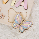Pastel-colored butterfly-shaped wooden puzzle piece on a light surface
