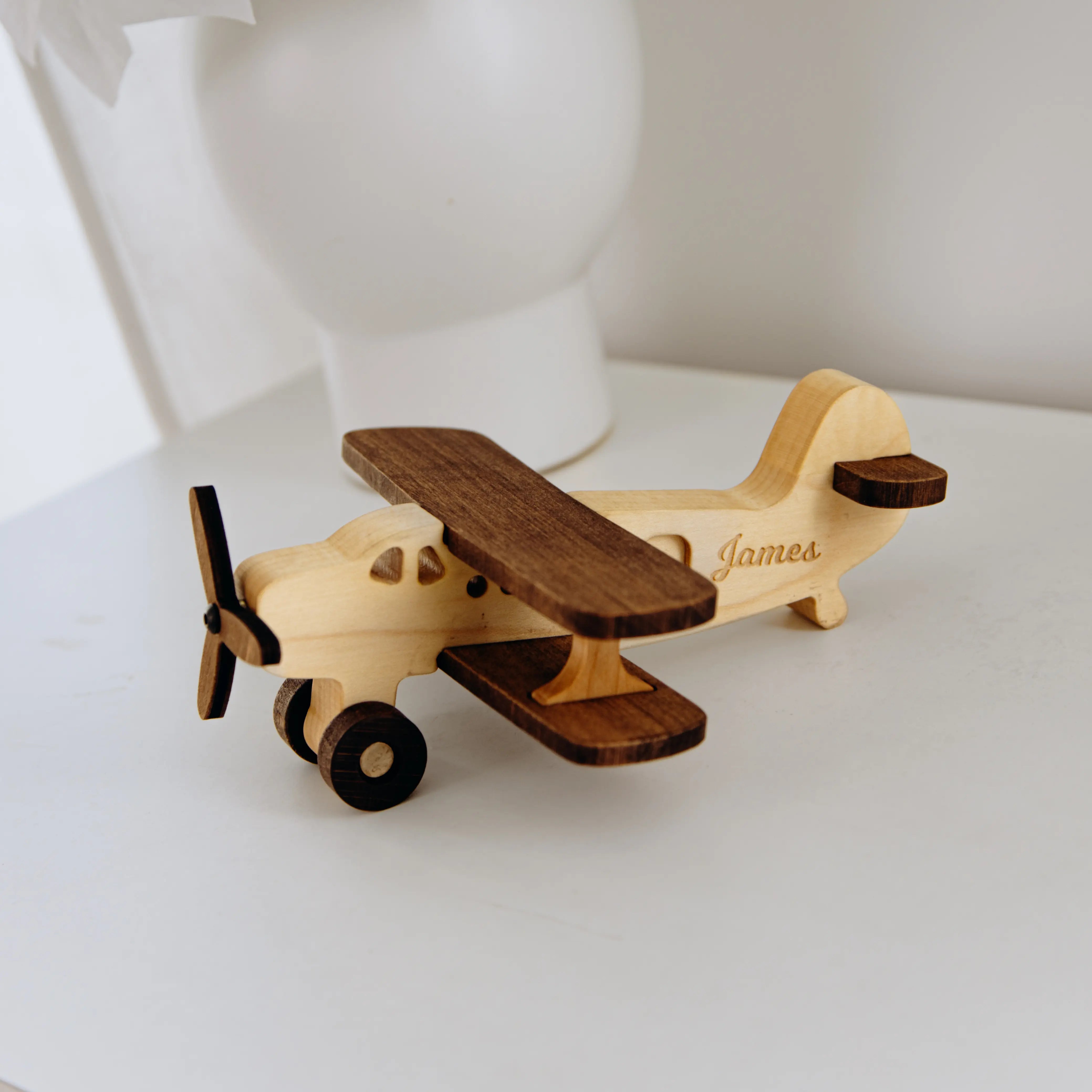 Wooden toy airplane with engraved name on a white surface