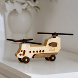 Wooden helicopter toy on a white surface with a blurred background