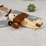 Two-tone wood biplane toy with engraved name James on a gray background