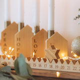 Decorative Advent calendar with wooden candle holders, featuring the words 'PEACE', 'HOPE, 'LOVE', 'JOY'.