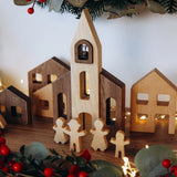 Wooden Christmas village scene with houses and figures on a white background