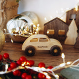 Wooden toy car with 'BusyPuzzle' branding on a decorative surface with lights and ornaments.