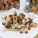 Wooden Christmas village set on a white surface with decorative elements.