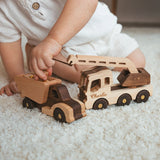 Child playing with wooden toy trucks on a carpeted floor