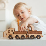 Child playing with a wooden toy truck set on a light background