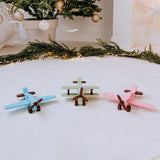 Three personalized wooden toy planes in mint, blue and pink with pine branches