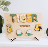 Wooden name puzzle spelling 'TIGER' on a stand, surrounded by plants.