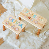 Two wooden name stools with personalized names and illustrations on a soft surface.